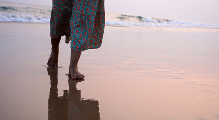 Female walking down a beach during a beautiful golden sunset. Tropical nature getaway concept.