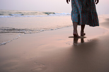 Female walking down a beach during a beautiful golden sunset. Tropical nature getaway concept.