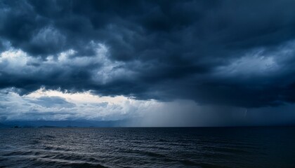 Fototapeta premium A dark, moody evening sky in shades of black and blue, with dramatic clouds creating a foreboding atmosphere. The scene captures the eerie stillness before a storm, evoking a sense of tension.