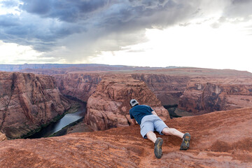 Adventurer peers over stunning Horseshoe Bend at sunset in Arizona