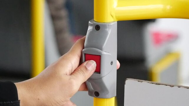 Using a hand to press a button to request a stop for the bus service