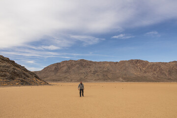 Hiker walking in a dry lake bedat The Racetrack at Death Valley National Park, California
