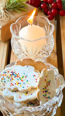 A jar with homemade Christmas cookies, gifts and lit candle on the table. Christmas dessert concept.