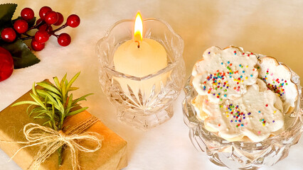 A jar with homemade Christmas cookies, gifts and lit candle on the table. Christmas dessert concept.