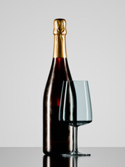 A bottle of wine and an empty wine glass close-up on a studio table.