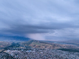 Drone view of the town and mountains at sunset. Beautiful clouds on the sky. Evening cityscape.