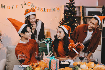 Group of young Asian man and women as friends having fun at a New Year's celebration, holding gift...