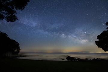 森の先にある浜辺から見る天の川と能登半島の星空