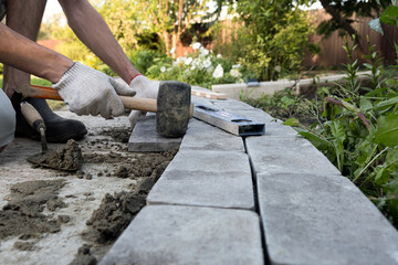 Laying paving stones on cement mortar. Laying a garden path made of tiles. Self-laying of concrete paving slabs in the courtyard of the house. do it yourself. DIY
