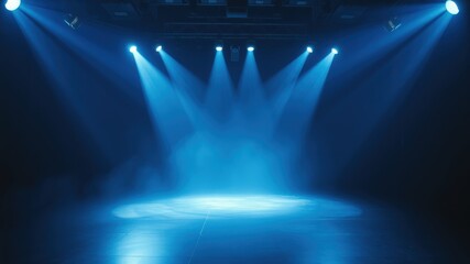 Stage lights illuminate a dark blue performance space with a spotlight focused on the center of the stage