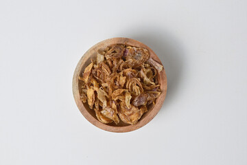 Top view of Indonesian crispy deep fried shallots or onion flakes (bawang goreng) in a wooden small bowl. Isolated on the white background.