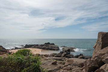 Expansive tropical ocean view with rocky shores under a bright, clear sky