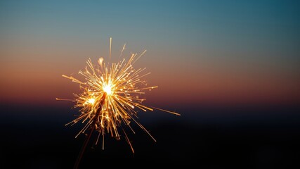 Fototapeta premium A single sparkler burns brightly against a colorful twilight sky, creating a dazzling display of light and movement.
