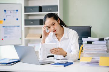 Woman who is tired and overthinking from working with tablet and laptop at modern office..