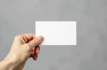 Female's hand holding blank business card on the grey background. Business card mockup