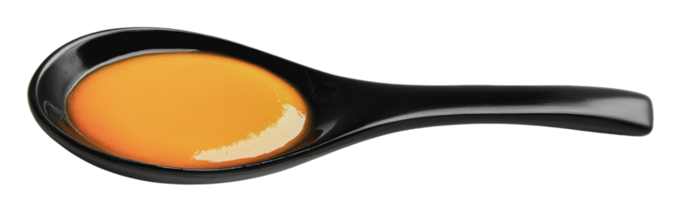 Spoon filled with sauce on a black dish, cut out - stock png.