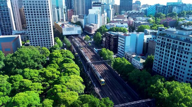 Drone aerial landscape of train on Sydney's Central station railway line tracks platform with trees in park Surry Hills CBD urban city metro buildings business