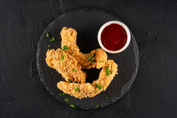 Chicken tenders. Fried chicken breast strips on black background. 