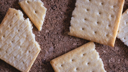 Closeup of crack biscuit cracker on brown wooden cork surface background.