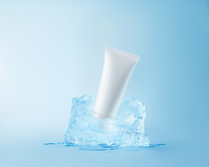 White tube frozen in piece of ice, soft blue color. Horizontal mockup, winter cosmetics concept, commercial photo