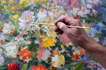 The artist paints a picture on canvas with oil paints.