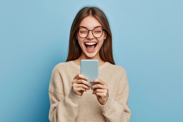 Fototapeta premium Young happy lucky woman student feeling excited winner holding cellphone using mobile phone