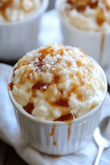 Creamy rice pudding dessert with caramel sauce and sea salt topping in white cups