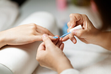 A skilled technician applies a vibrant nail polish while pampering a woman at a stylish salon. The atmosphere is relaxing, showcasing the latest nail trends and techniques.