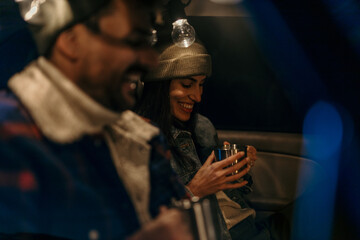 Cozy couple in a car trunk talking and sipping hot beverages on a chilly evening