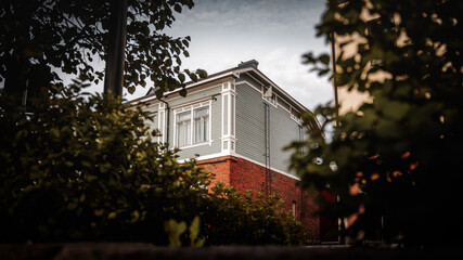 Old wood and brick house with trees and bushes on foreground