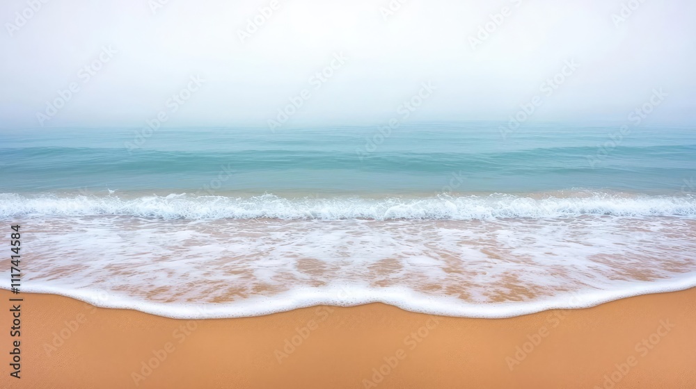 Aufkleber serene beach scene with gentle waves lapping at golden sand on a foggy day.