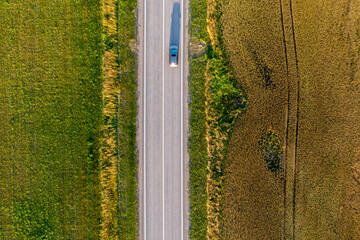 Aerial View of Cars Driving on Rural Road Through Green and Brown Fields