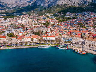 Aerial view of Makarska city center with its vibrant waterfront, yachts, traditional architecture, and the stunning Adriatic Sea coastline