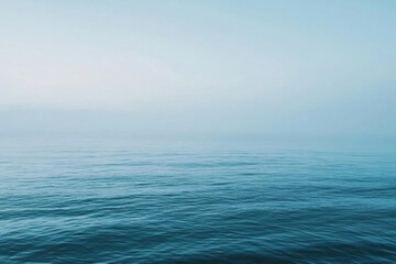 Obraz premium A serene view of calm ocean waters under a soft blue sky.