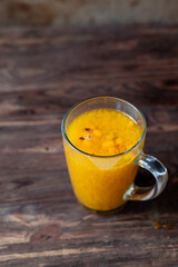 Sea buckthorn tea with orange, cinnamon and rosemary in glasses on wooden table. put the tea on the table
