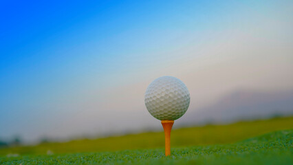 Golf ball on green grass in the evening golf course with sunshine background.