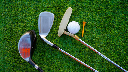 Golf clubs and golf balls on a green lawn in a beautiful golf course with morning sunshine.