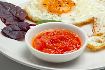 Fried egg and red sauce on the plate.
