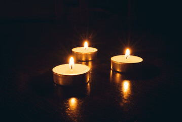 Three burning candles on a black background.