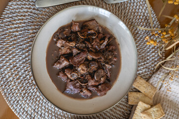 plate of meat with wine sauce on a wooden table in a house