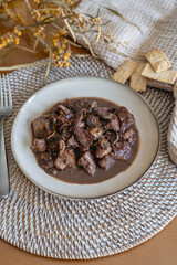 plate of meat with wine sauce on a wooden table in a house