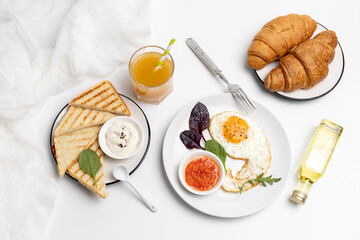 Fried egg on the plate, croissants and toasts with cheese sauce.