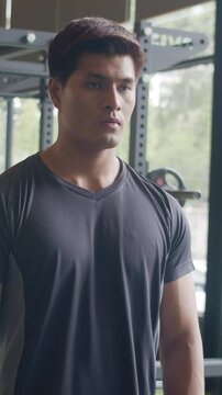 Vertical Screen : Handsome asian guy take out shirt naked torso body look at his muscles and trained body at mirror in fitness. Bodybuilder male model posing, Fitness in gym, sport lifestyle concept.