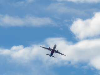 Flying airplane on o cloudy sky. Real plane in the sky view from down up