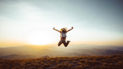 Happy man with arms up jumping on the top of the mountain - Successful hiker celebrating success on...