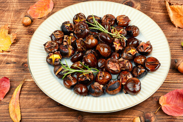 Cracked roasted chestnuts on rustic wooden table.