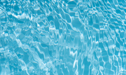 Blue water with ripples on the surface. Defocus blurred transparent blue colored clear calm water surface texture with splashes and bubbles. Water waves with shining pattern texture background.