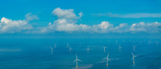 Tall windmill turbines against a clear blue sky, generating renewable energy in the serene Go Cong, Vietnam landscape by the sea. Like windmill park Westermeerdijk in the Noordoostpolder Netherlands.