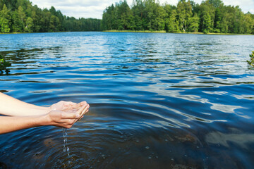 Person scooping raw water from lake to promote environmental awareness in natural resource conservation