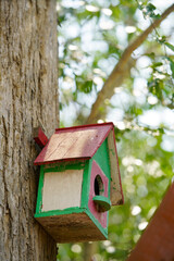 Colorful Wooden Birdhouse Hanging on Tree Against Blurred Background
